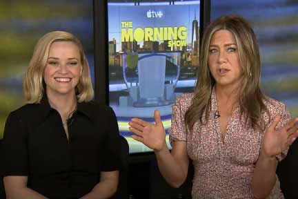 Reese Witherspoon smiles while Jennifer Anniston speaks